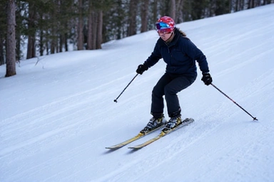 An intermediate skier performing parallel turns on a blue square run, with good form and speed
